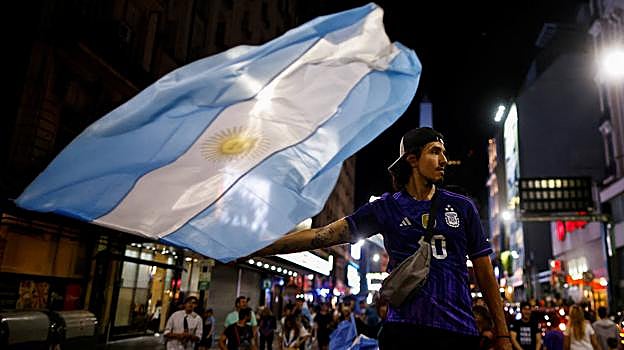 Un joven celebra con una bandera argentina la victoria de Milei