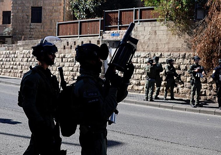 Oficiales de la policía fronteriza israelí hacen guardia mientras los palestinos musulmanes intentan realizar las oraciones del viernes en una carretera en las afueras de la Ciudad Vieja de Jerusalén