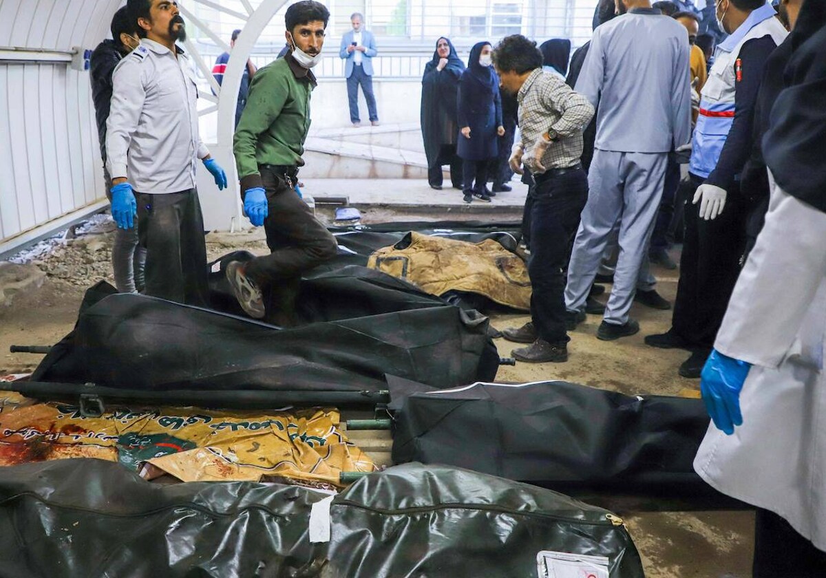 Eine Gruppe von Menschen versammelt sich neben den Leichen der Opfer des Doppelangriffs, bei dem in Kerman (Iran) Dutzende Menschen ums Leben kamen