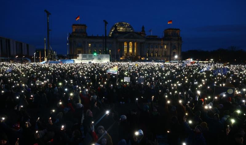 Los participantes encienden sus teléfonos móviles durante una manifestación contra el racismo y la política de extrema derecha frente al edificio del Reichstag en Berlín