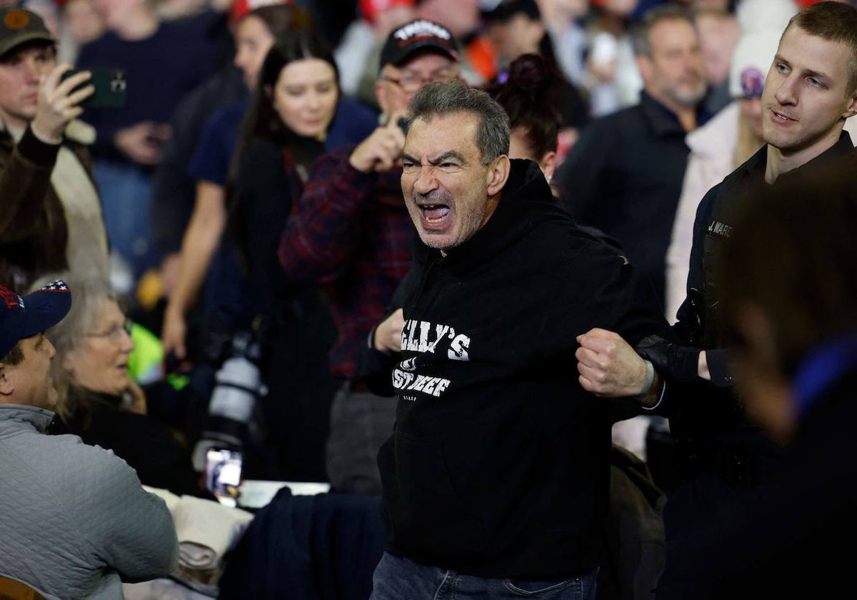 Un agente de Policía retira a un hombre por protestar contra Donald Trump en un mitin celebrado en Mánchester (New Hampshire). El expresidente podría enfrentarse a Joe Biden en noviembre de 2024