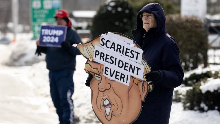 Un partidario y un detractor de Trump sostienen carteles en su favor y en su contra