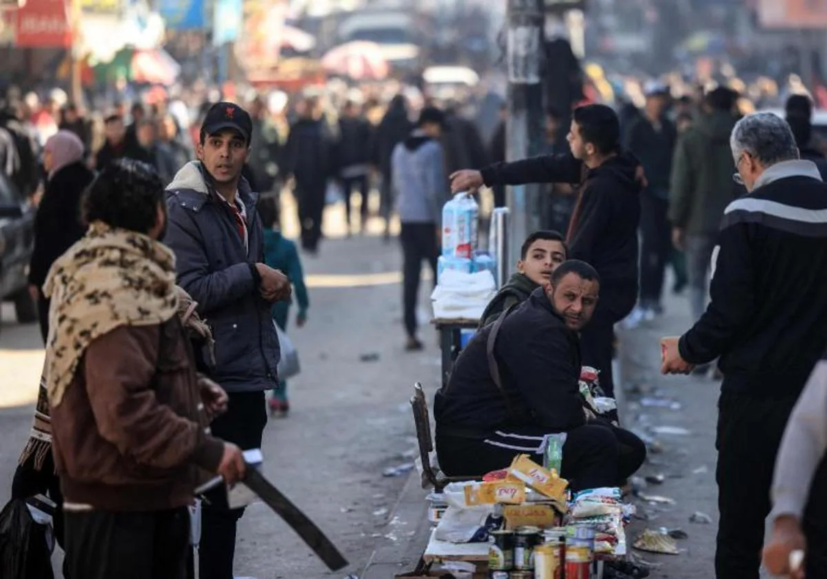 Personas que huyeron de los combates en la Franja de Gaza venden alimentos en una calle abarrotada en Rafah, en la parte sur del territorio palestino