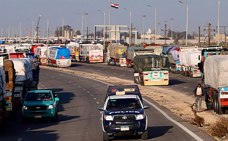Imagen principal - Cientos de camiones cargados con ayuda humanitaria hacen cola para entrar en Gaza por el paso fronterizo de Rafah (imagen superior), lo que Egipto achaca a los controles israelíes. Por este cruce no solo llega la asistencia a los palestinos, sino que también salen los heridos evacuados a hospitales de Egipto y otros países. Estos últimos son trasladados desde el cercano aeropuerto de El Arish (arriba a la izquierda), como Amina, una niña de 13 años que perdió a su padre en un bombardeo israelí y será tratada de la sangre que se le acumula en los ojos en Qatar (arriba a la derecha).  