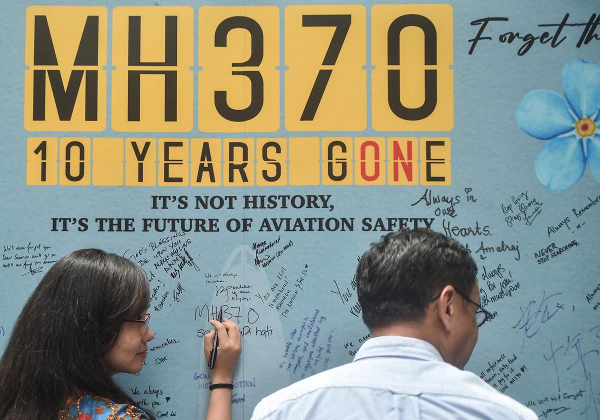 Una mujer escribe un mensaje durante un acto celebrado por familiares de los pasajeros para conmemorar el décimo año desde que el vuelo MH370 de Malaysia Airlines