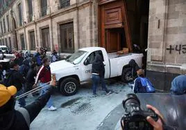 Manifestantes de Ayotzinapa derriban con un vehículo la puerta del palacio presidencial en México
