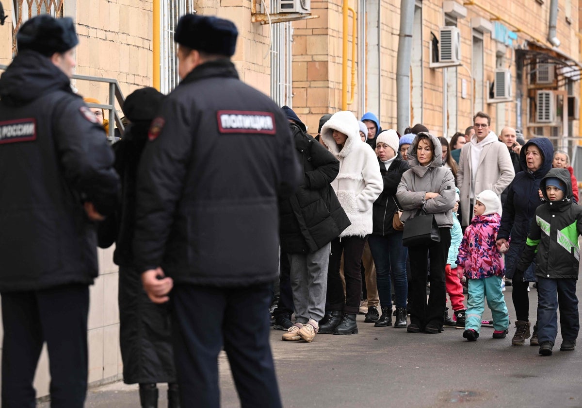 Un grupo de personas acude a votar a un colegio electoral de Moscú bajo la vigilancia de la Policía