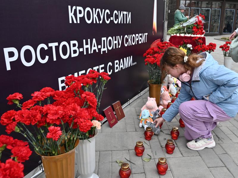 Una mujer coloca un juguete en un monumento improvisado