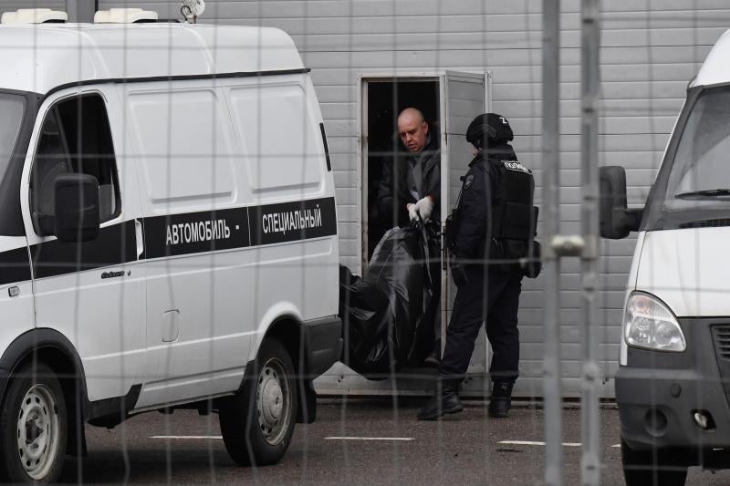 Especialistas suben a un vehículo el cuerpo de una víctima del tiroteo