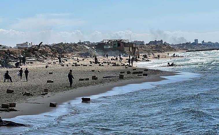 Imagen principal - Doce palestinos mueren ahogados al intentar coger paquetes de comida lanzados desde un avión de Estados Unidos al mar en Gaza