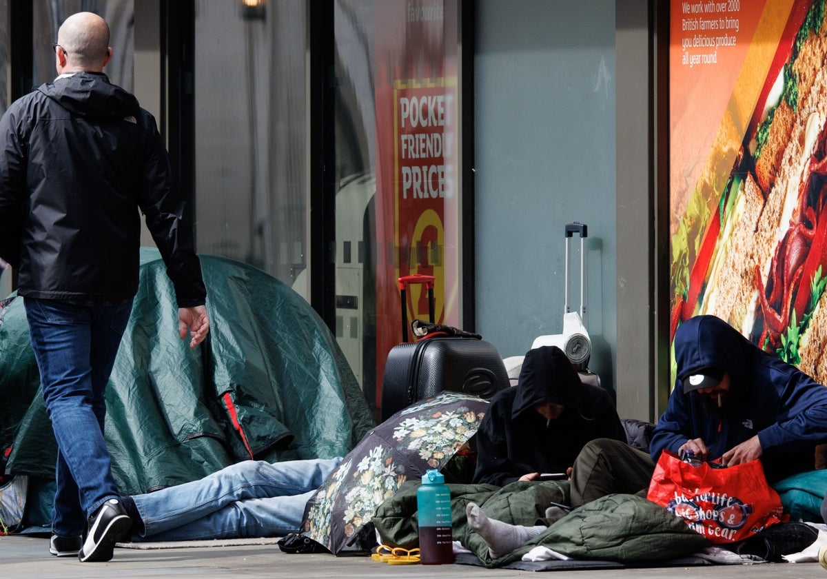 Un grupo de personas sin hogar junto a una tienda de comestibles de Londres