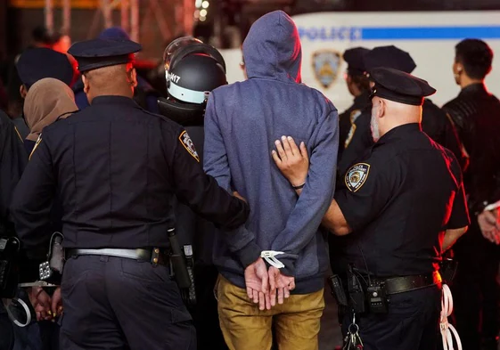 La policía detiene a un manifestante, mientras otros agentes de policía entran en el campus de la Universidad de Columbia