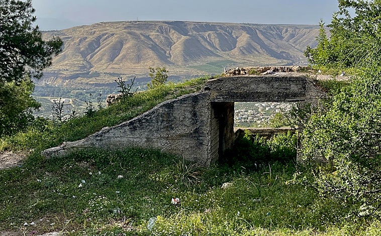 Imagen principal - En el valle del Jordán se resumen buena parte de los agravios históricos de Oriente Próximo, como se ve en este búnker abandonado del Ejército jordano bajo los Altos del Golán (imagen superior). Frente a los recelos hacia Irán por ser chií, en Jordania se sigue viendo mucho cariño al difunto dictador de Irak, Sadam Husein (arriba a la izquierda). Como recuerdo de la sangrienta guerra civil en la vecina Siria, en el cementerio de Ramtha están enterrados algunos de sus 'mártires', como se denomina a los rebeldes que lucharon contra el régimen de Al Assad (arriba a la derecha)