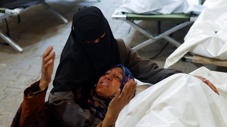 Dos mujeres lloran delante de un cadáver tras los bombardeos en Rafah del Ejército israelí