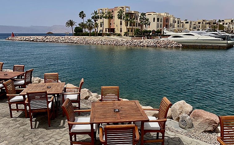 Imagen principal - Otro de los destinos más populares de Jordania, el mar Rojo, también ha sufrido una drástica reducción de turistas, primero por la guerra en Gaza y ahora por el ataque de Irán contra Israel con cientos de misiles y drones en abril. Así se aprecia en hoteles y complejos de vacaciones de lujo como Grand Tala Bay (imagen superior), en los restaurantes y tiendas de suvenires que pueblan la carretera de Amán a Áqaba (arriba a la izquierda) y en sus playas de arena blanca y fondos de coral (arriba a la derecha), que están desiertas