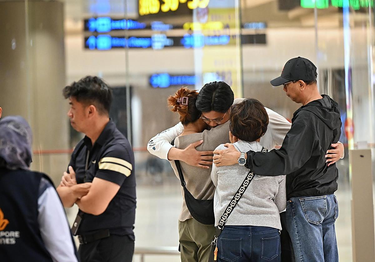 Pasajeros del vuelo Londres-Singapur después de aterrizar en el país asiático, arropados por familiares