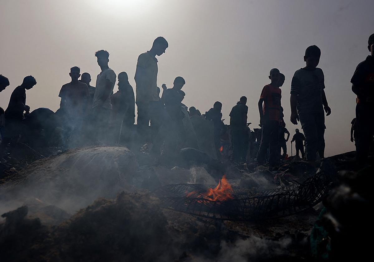 Varias personas se reúnen en el lugar de un ataque israelí contra un campo para desplazados internos en Rafah.