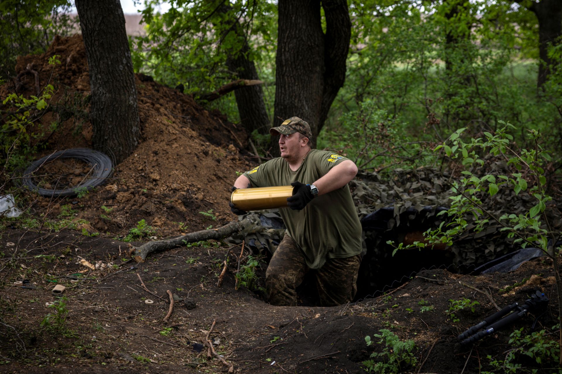 Imagen principal - La 57.ª Brigada Motorizada de Ucrania lleva un proyectil para un obús, en medio del ataque de Rusia contra Ucrania