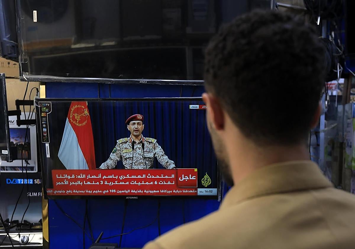 Una persona observa al portavoz militar hutí, Yahya Sarea, pronunciar una declaración televisada sobre nuevos ataques marítimos