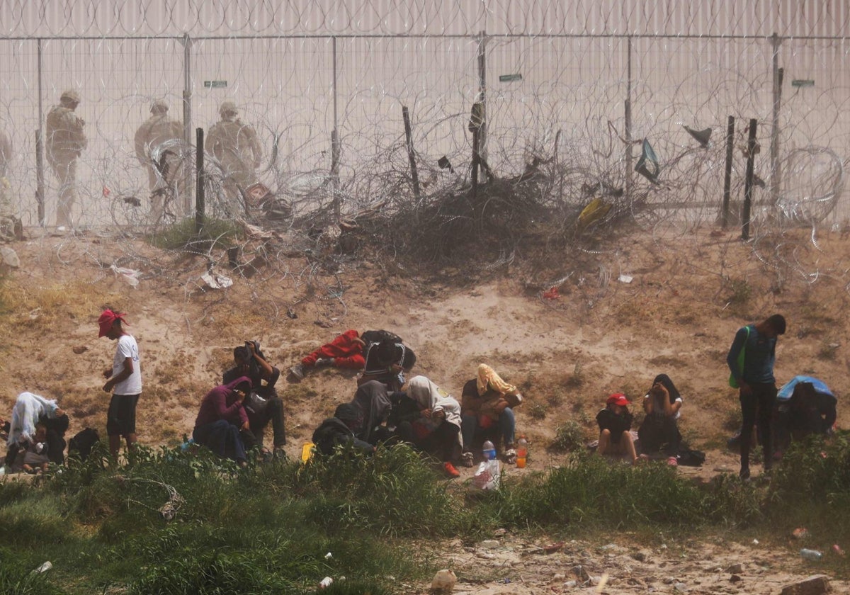 Peticionarios de asilo son observados por la guardia fronteriza de Texas, tras cruzar desde Ciudad Juárez