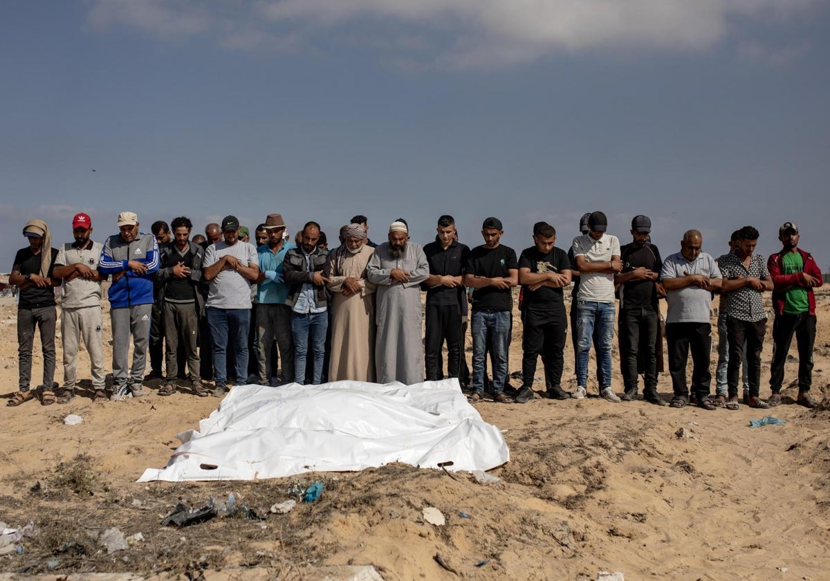 Palestinos rezan junto a los cuerpos de sus familiares muertos cerca de Jan Yunis