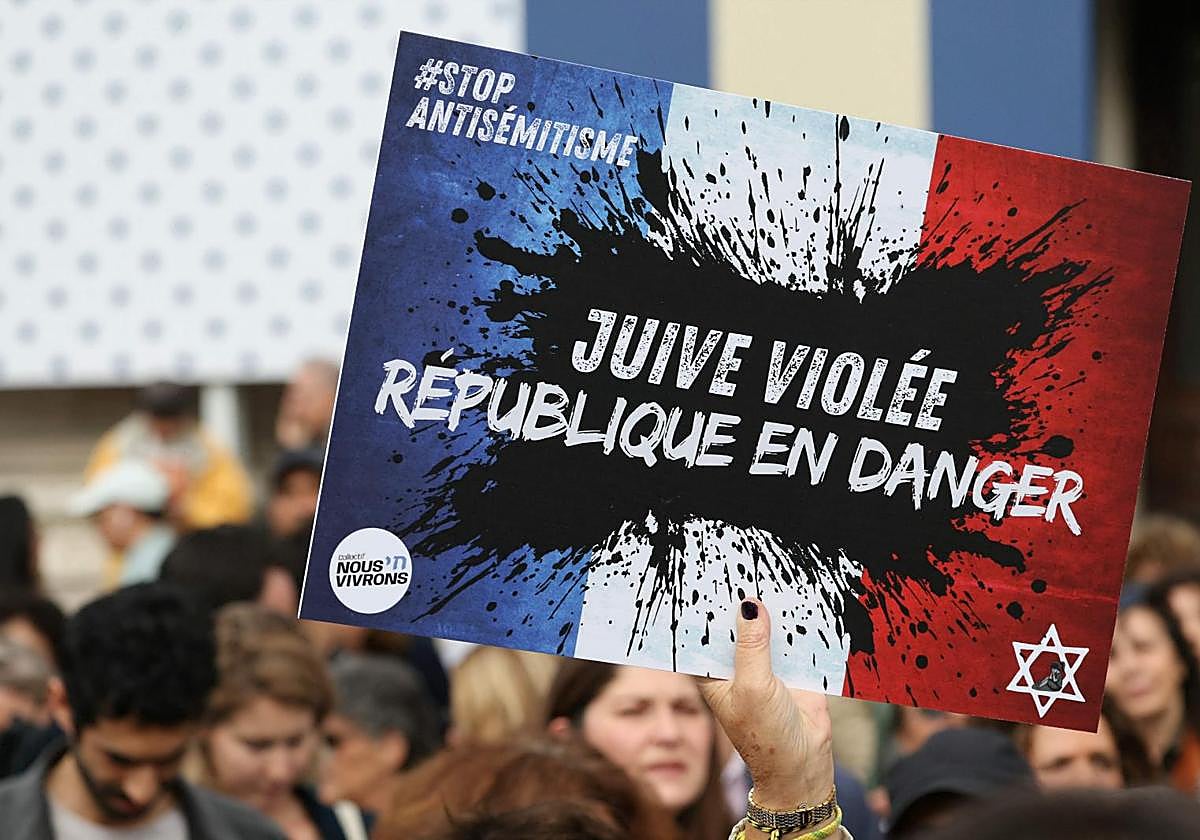 Un manifestante sostiene un cartel que dice: «Niña judía violada, República en peligro»