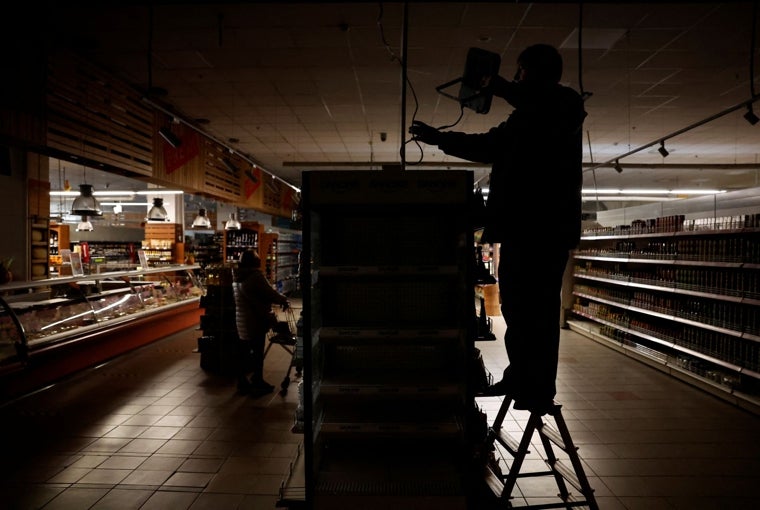 Un trabajador de un supermercado instala una luz alimentada por un generador mientras Járkov sufre un corte de electricidad, en una foto de archivo