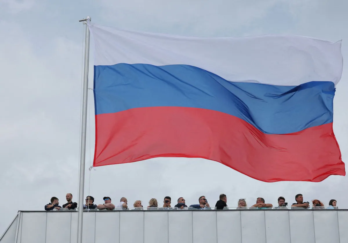 Algunas personas se reunen junto a una gran bandera rusa en Kronstadt, cerca de San Petersburgo