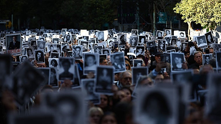 Personas sostienen fotografías de víctimas