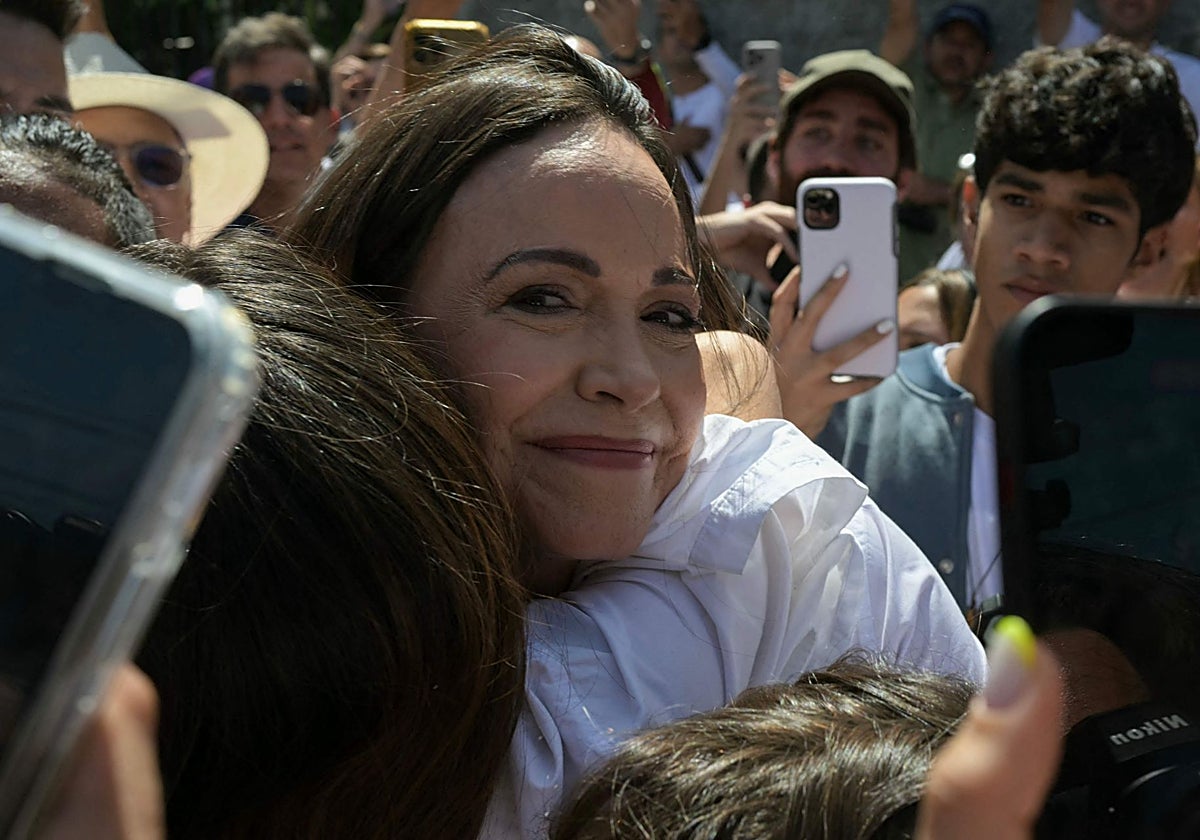 La líder opositora venezolana María Corina Machado es recibida por un simpatizante cuando sale del colegio electoral en Caracas