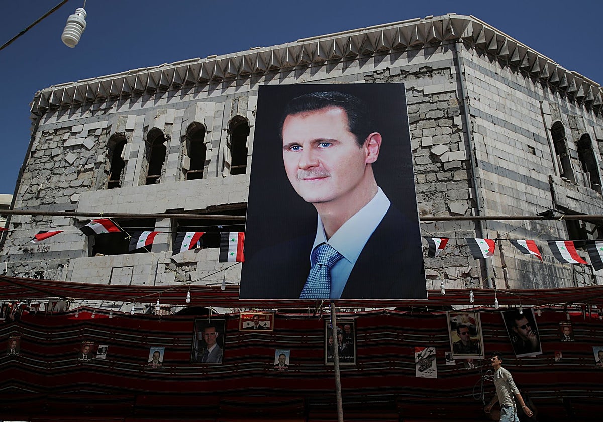 Un hombre camina frente a una fotografía del presidente Bashar al-Assad en Douma, Siria