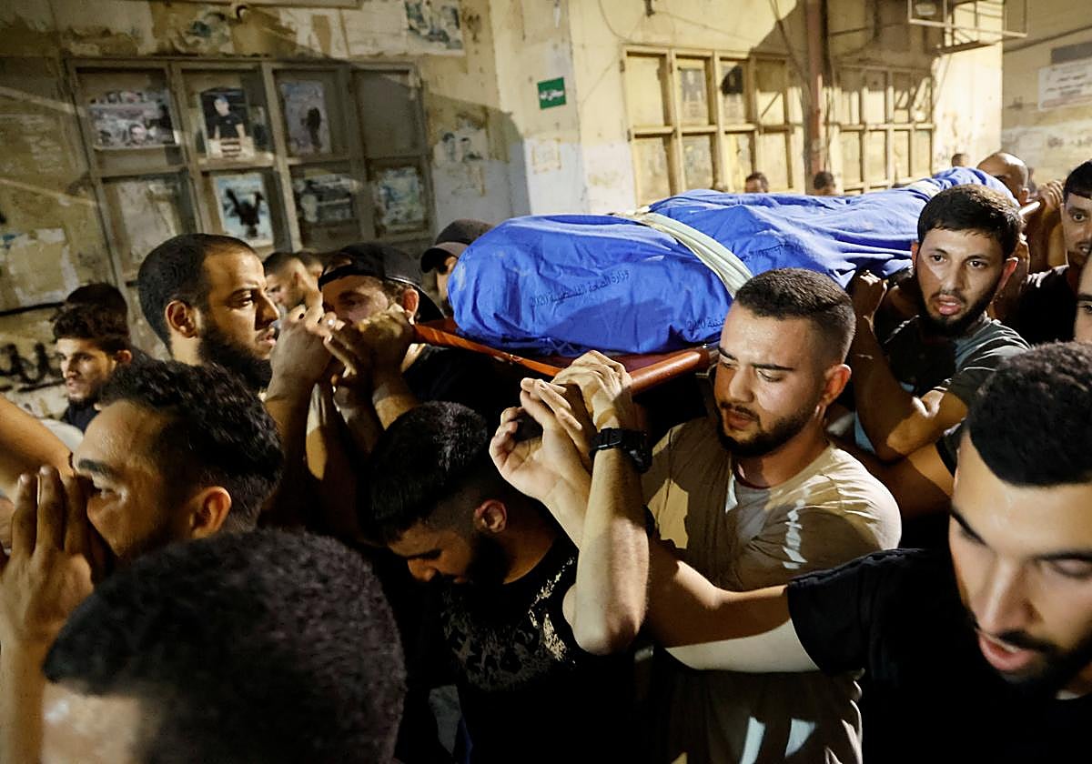 Ciudadanos gazatíes transportan los cuerpos de los dos fallecidos por el ataque a un vehículo en Yenín