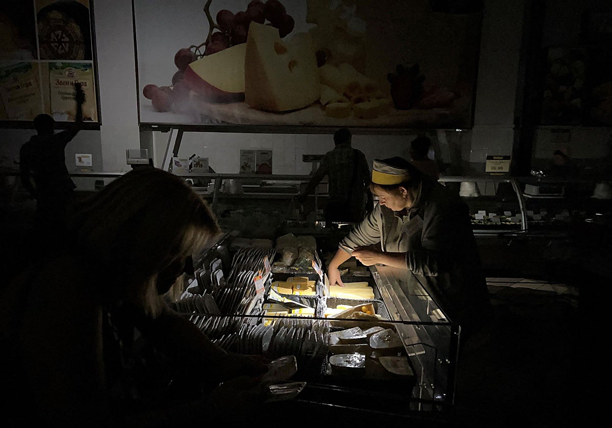 Una vendedora tiende a un cliente en un supermercado durante un apagón en Kiev