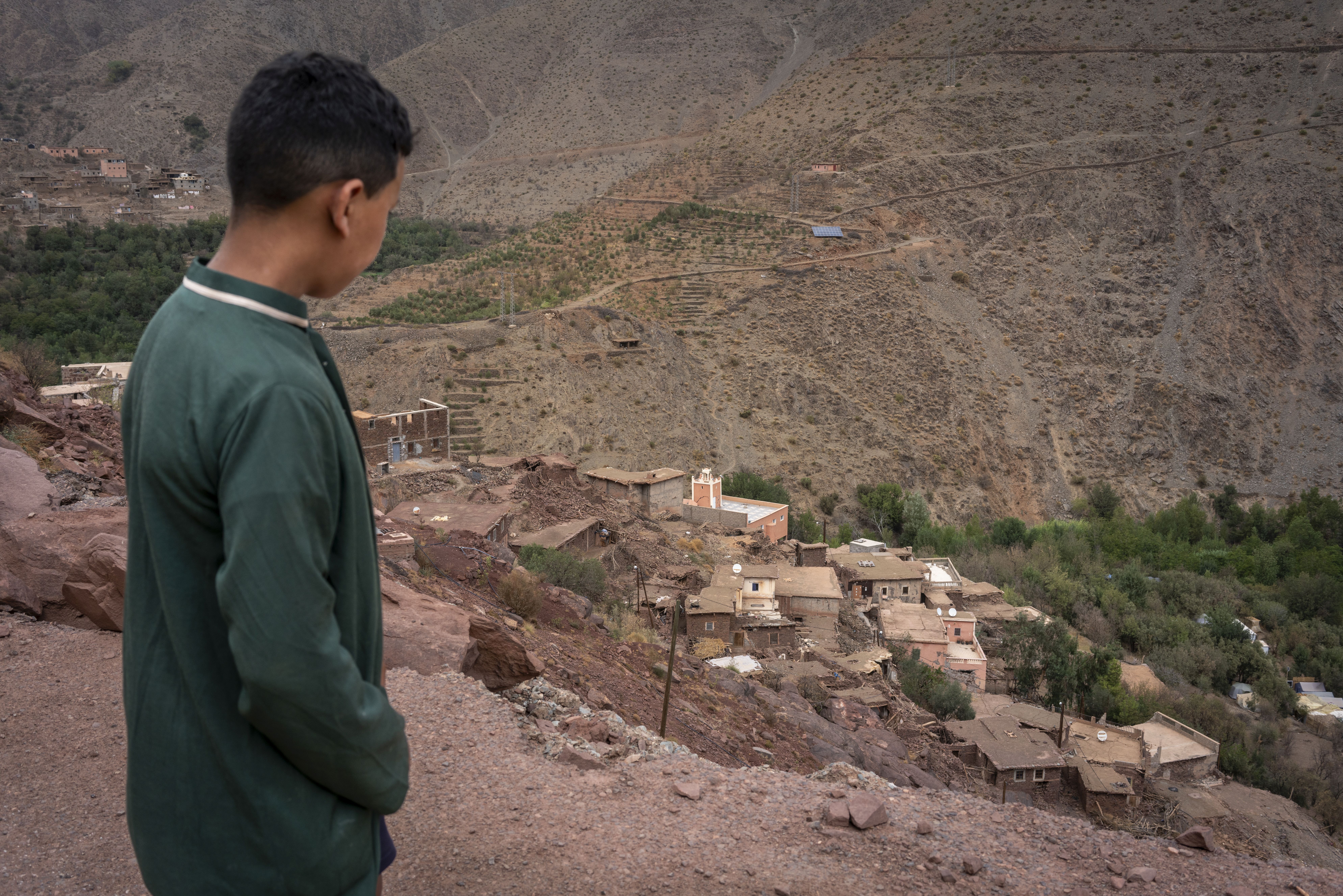 Un niño observa desde la carretera un pueblo destruido por el terremoto