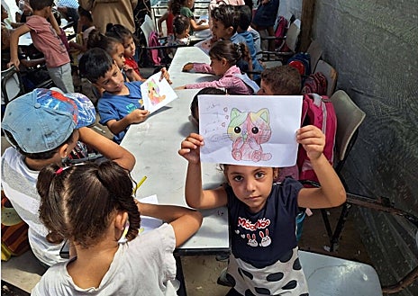 Imagen secundaria 1 - Desde que empezó la guerra de Gaza en octubre, más del 70 por ciento de las escuelas han resultado destruidas o dañadas. Sin libros, ni lápices, ni pupitres, ni pizarras, los 170 niños que estudian en las aulas improvisadas que dirige la profesora Jaldia al Hasheim intentan no perder su educación, ni su infancia, bajo las bombas del Ejército israelí