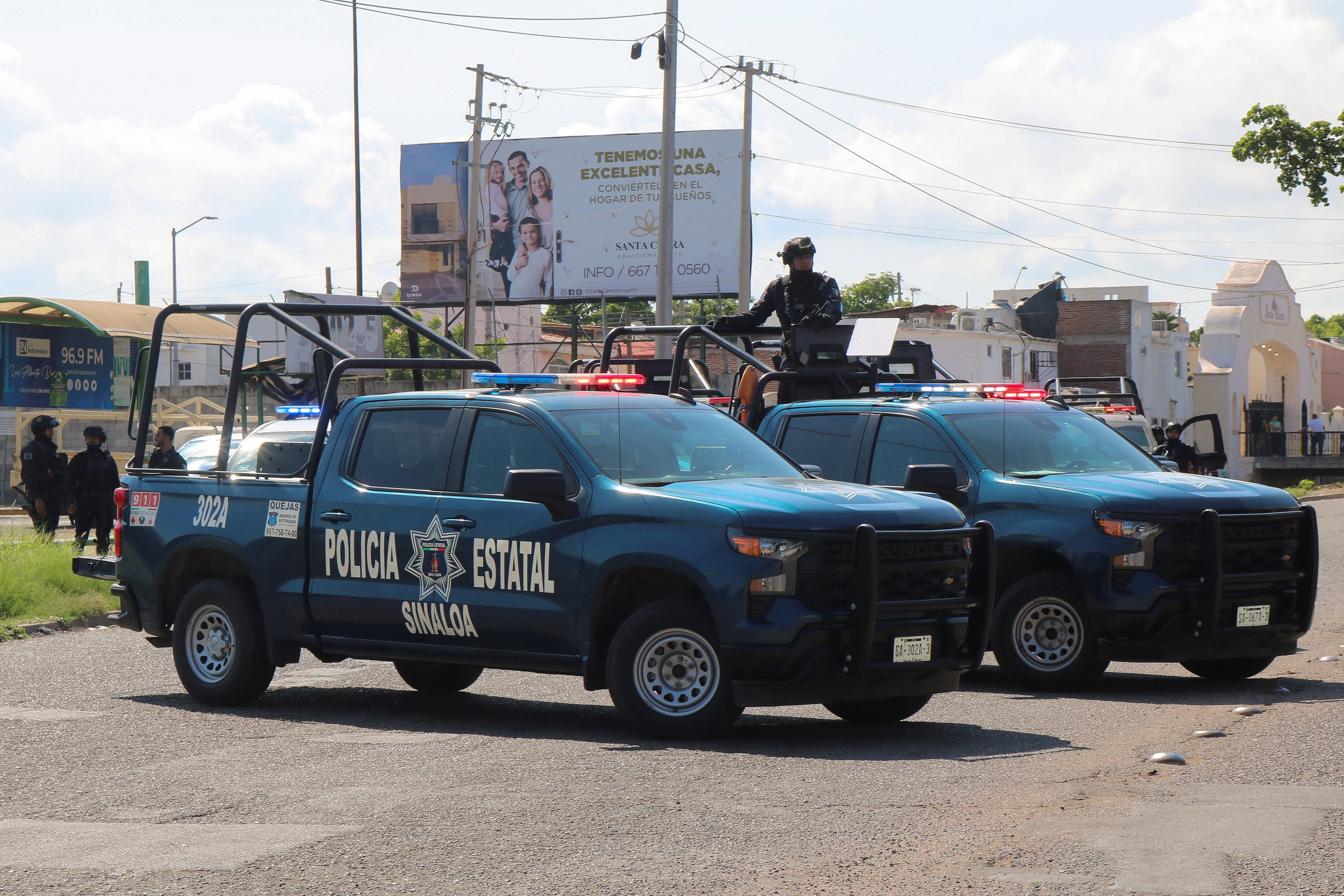 Policías del estado de Sinaloa acuden al lugar donde un camión de reparto ha sido quemado.