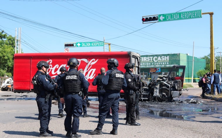 Imagen principal - Arriba, policias observan un camión calcinado; debajo, a la izquierda, una camioneta con disparos en su carrocería; a la derecha, un vehículo ardiendo