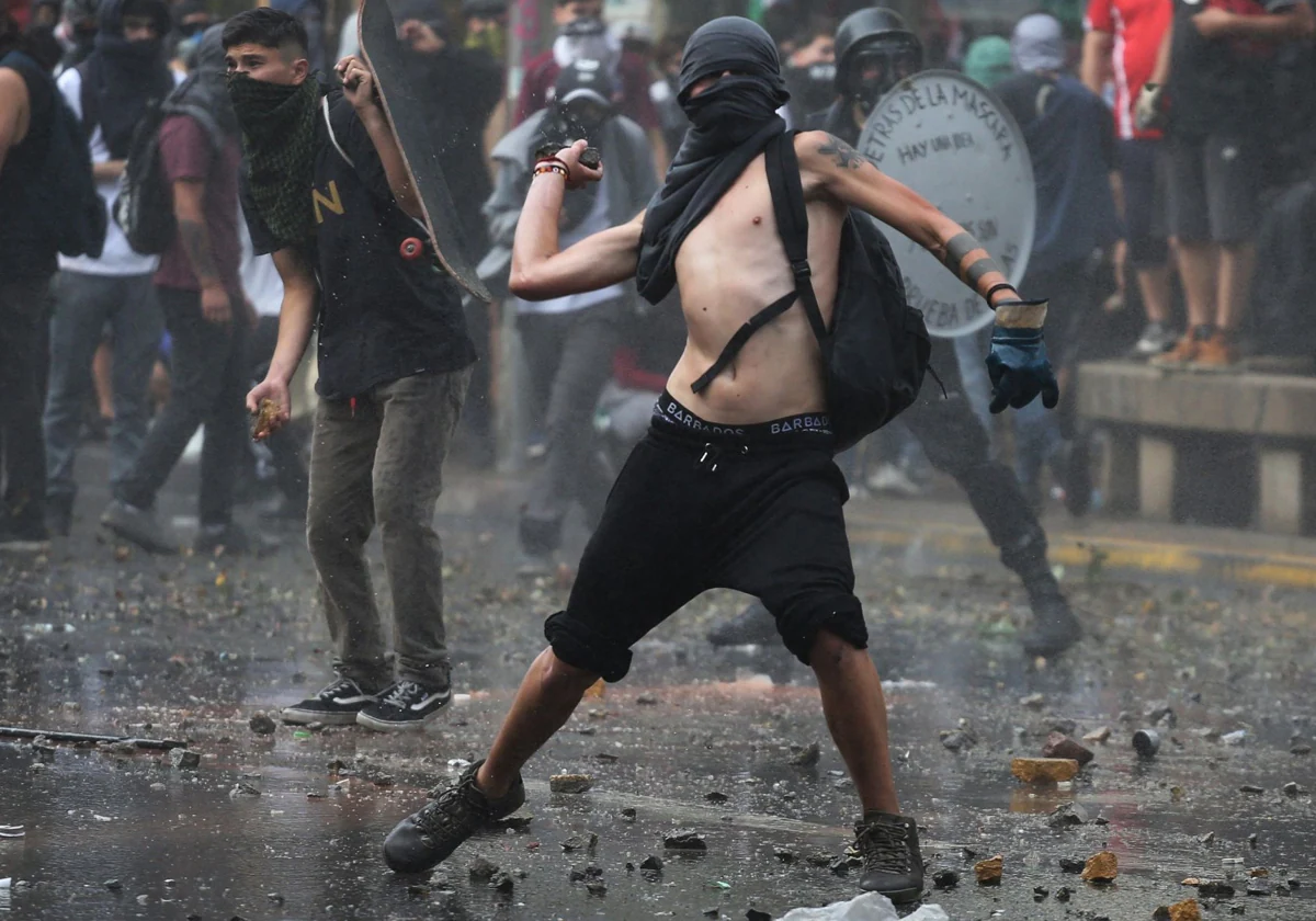 Un participante del estallido social de 2019 lanza una piedra contra la Policía