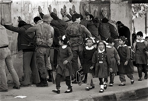 Unas niñas palestinas regresan del colegio mientras unos soldados israelíes registran a unos detenidos en la Franja de Gaza (1986)