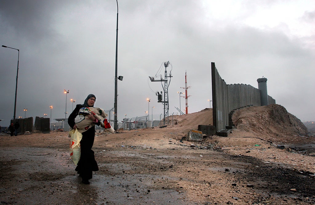 Una mujer camina junto al entonces recién construido muro por Israel en Ramala (2005)