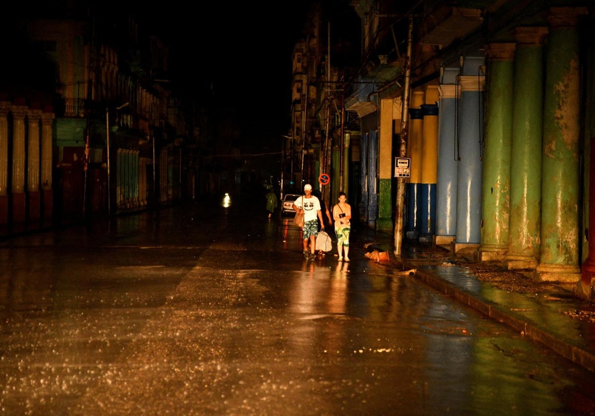 La gente camina por la calle mientras la red eléctrica sufre un apagón total mientras el huracán Rafael toca tierra en la provincia de Artemisa