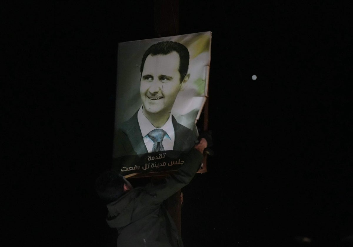 Los combatientes antigubernamentales rompen un cartel del presidente sirio Bashar al Assad