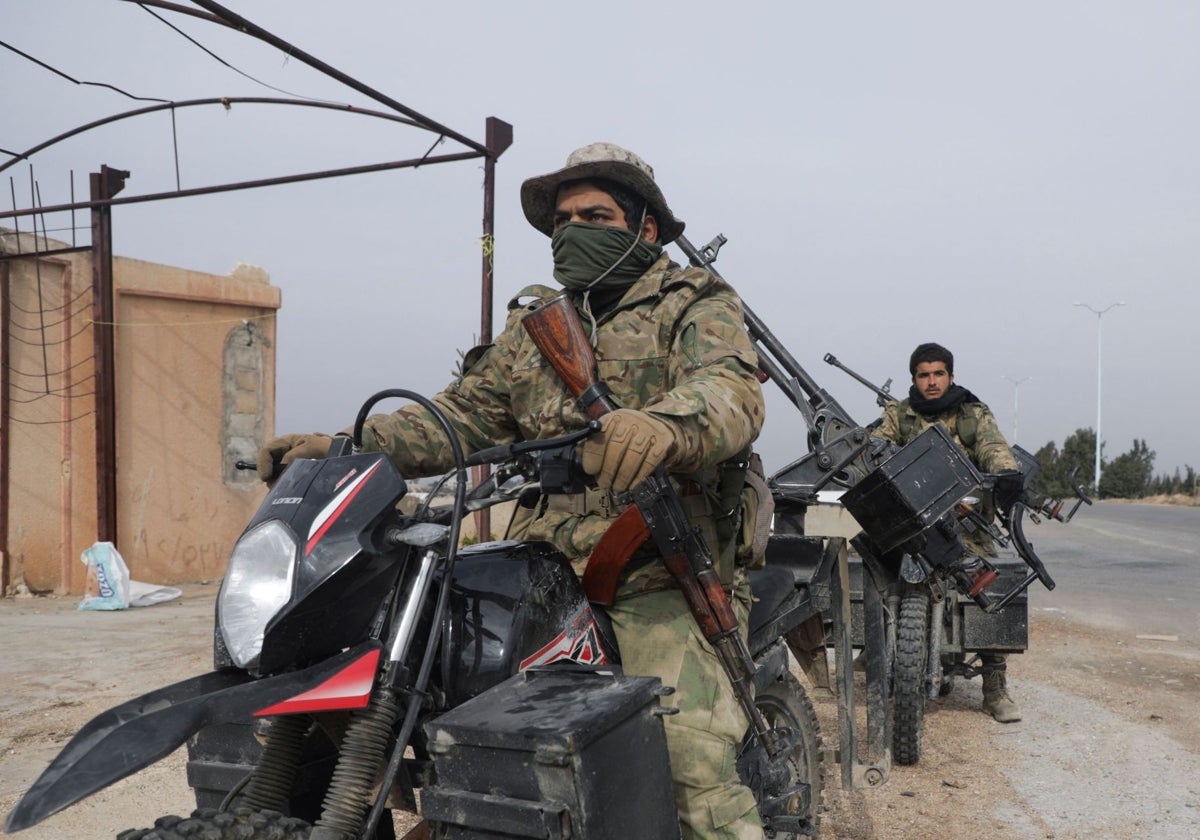 Combatientes rebeldes sentados en una motocicleta en el campo de Homs