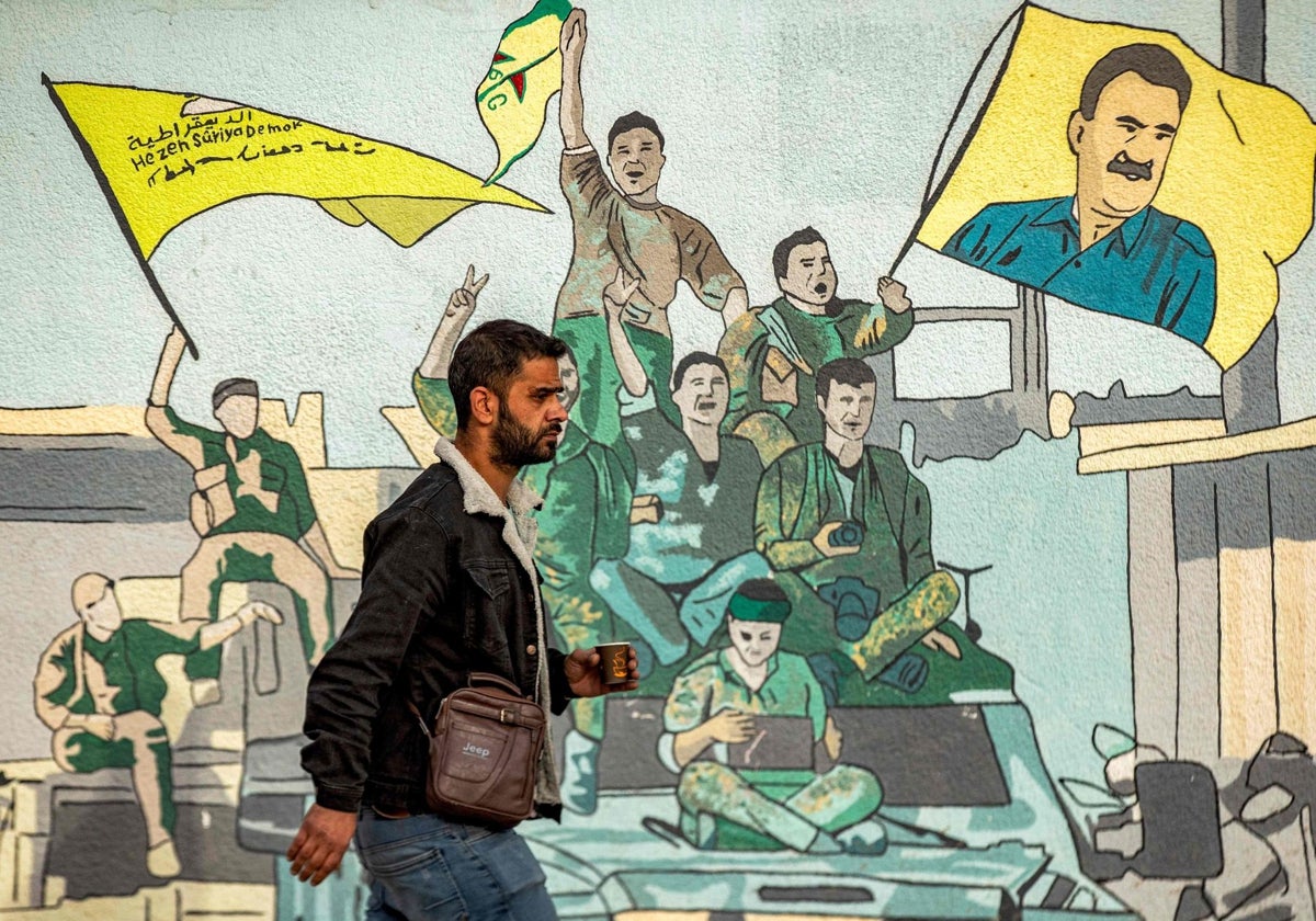 Un hombre pasa junto a un mural que representa a partidarios de las Fuerzas Democráticas Sirias (FDS)