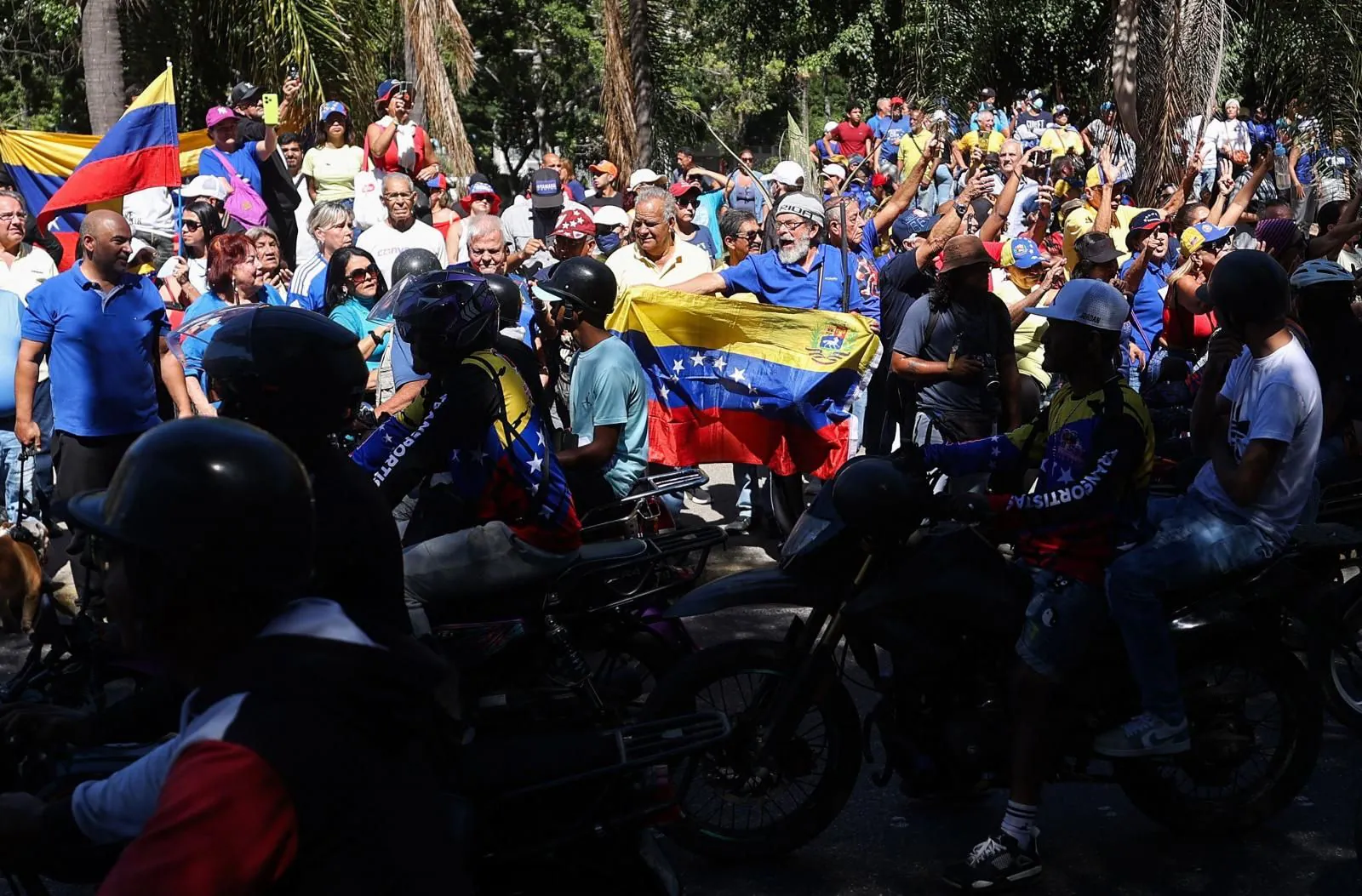 Manifestantes antigubernamentales gritan consignas mientras partidarios del presidente venezolano Nicolás Maduro pasan en motocicletas