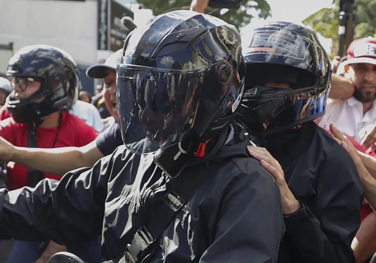 La líder antichavista María Corina Machado (d, casco negro) se retira de una manifestación este jueves, en Caracas (Venezuela)