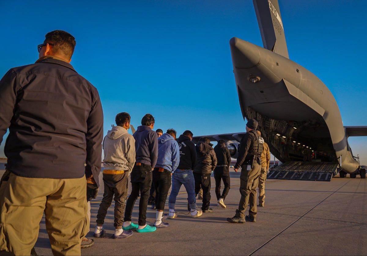 Un grupo de inmigrantes ilegales caminando hacia el avión que los deportará