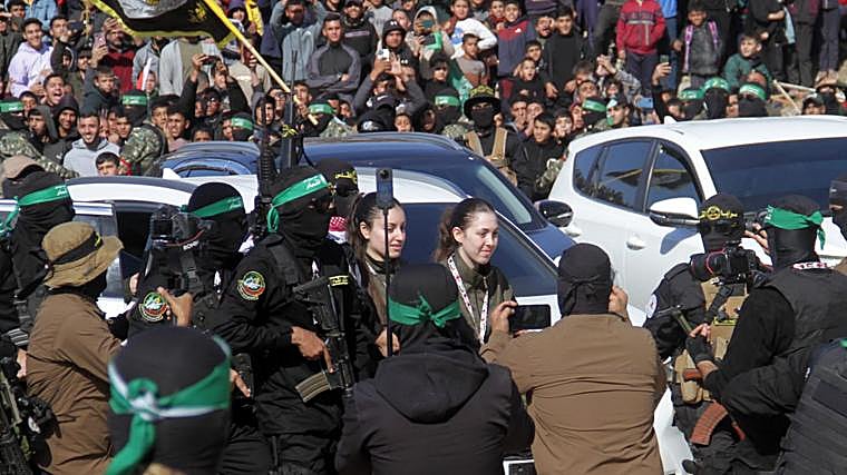 Las rehenes israelíes Naama Levy (c, dcha) y Karina Ariev (c, izq) caminan antes de ser entregados al representante del Comité Internacional de la Cruz Roja