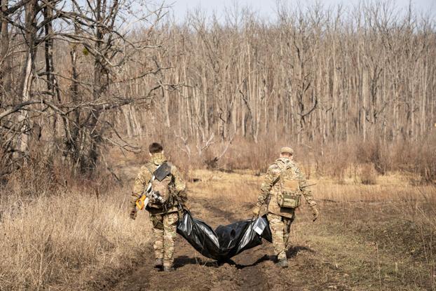 Artur y Oleksiy cargan los restos mortales del soldado