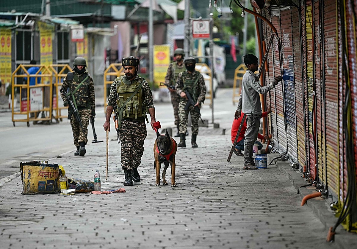Soldados paramilitares indios patrullan un mercado en Srinagar el 10 de mayo de 2025 con un perro rastreador.
